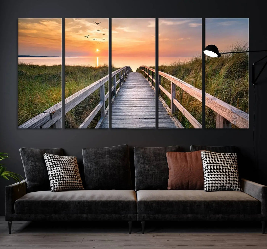 The Sunset Lakeside Pier Wall Art Canvas Print depicts a boardwalk leading towards a sunset over the ocean, framed by grassy dunes. Each piece is meticulously hand-assembled using museum-quality canvas to guarantee durability and vibrant colors.