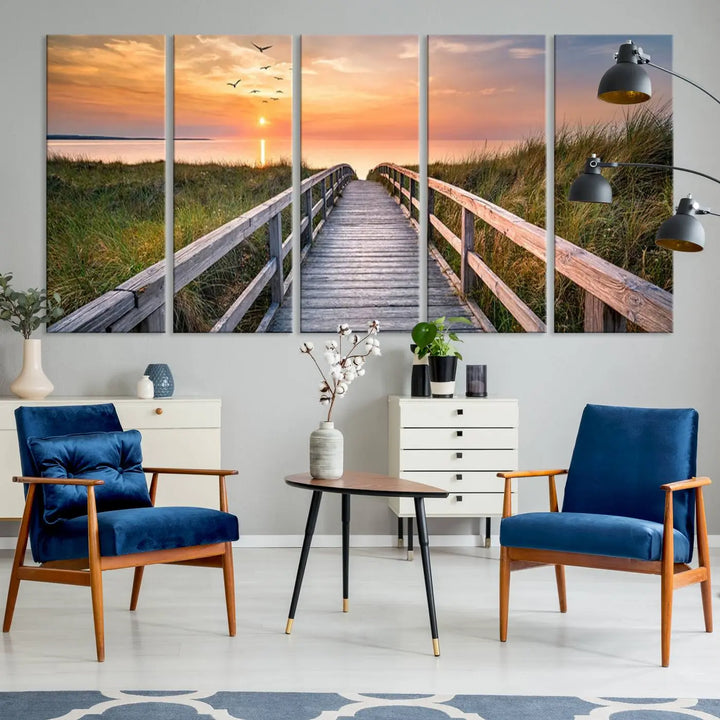 The Sunset Lakeside Pier Wall Art Canvas Print depicts a boardwalk leading towards a sunset over the ocean, framed by grassy dunes. Each piece is meticulously hand-assembled using museum-quality canvas to guarantee durability and vibrant colors.