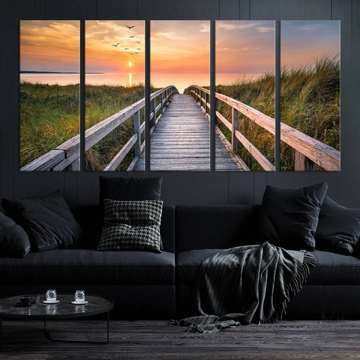 The Sunset Lakeside Pier Wall Art Canvas Print depicts a boardwalk leading towards a sunset over the ocean, framed by grassy dunes. Each piece is meticulously hand-assembled using museum-quality canvas to guarantee durability and vibrant colors.