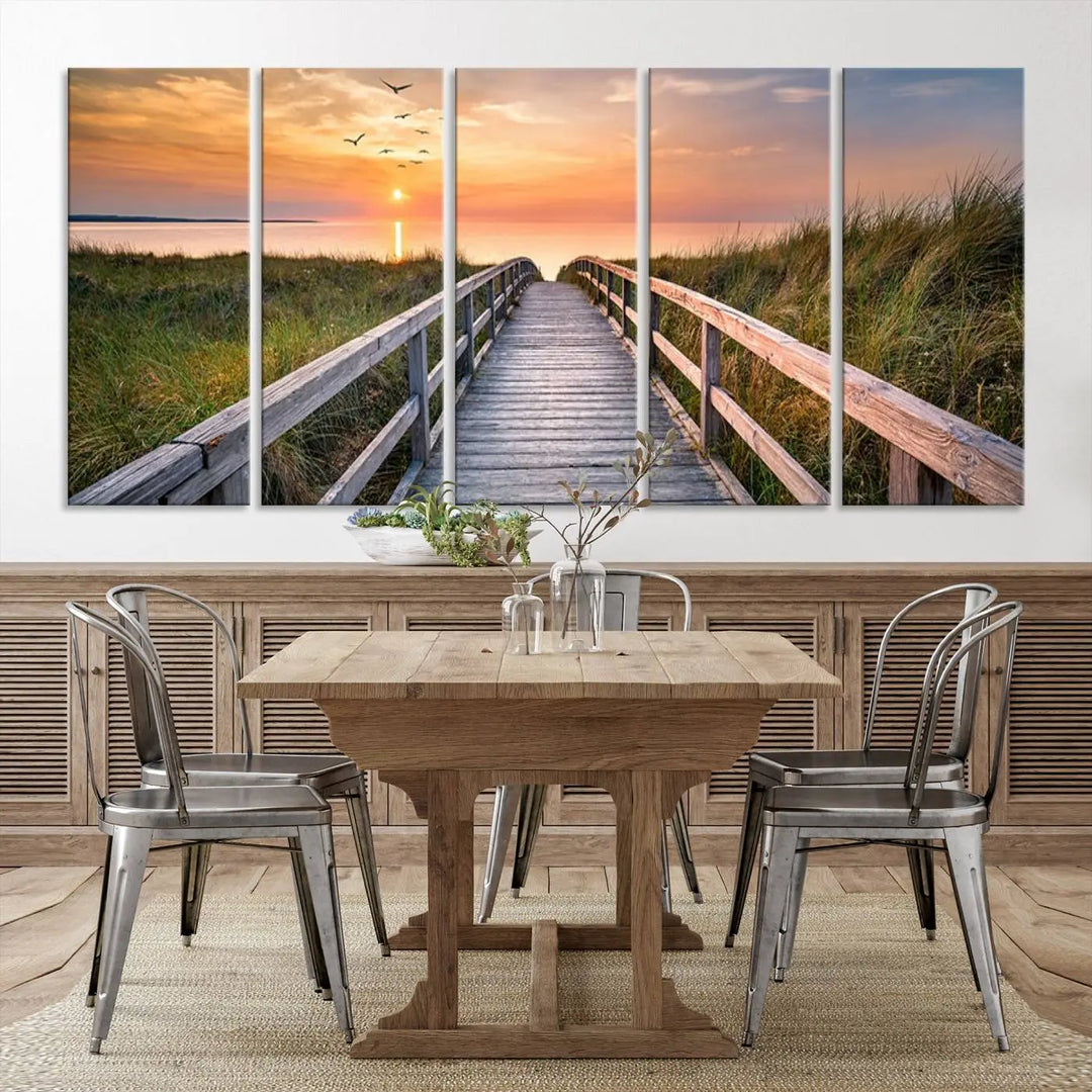 The Sunset Lakeside Pier Wall Art Canvas Print depicts a boardwalk leading towards a sunset over the ocean, framed by grassy dunes. Each piece is meticulously hand-assembled using museum-quality canvas to guarantee durability and vibrant colors.