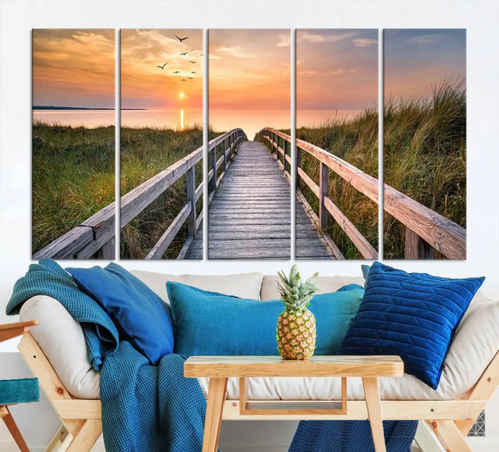 The Sunset Lakeside Pier Wall Art Canvas Print depicts a boardwalk leading towards a sunset over the ocean, framed by grassy dunes. Each piece is meticulously hand-assembled using museum-quality canvas to guarantee durability and vibrant colors.