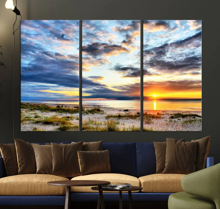 The living room features the Sunset On The Ocean Wall Art Canvas Print, a stunning large triptych depicting a sunset over a beach. This artwork is elegantly displayed on museum-quality canvas with UV-protective coating, ensuring both beauty and durability.