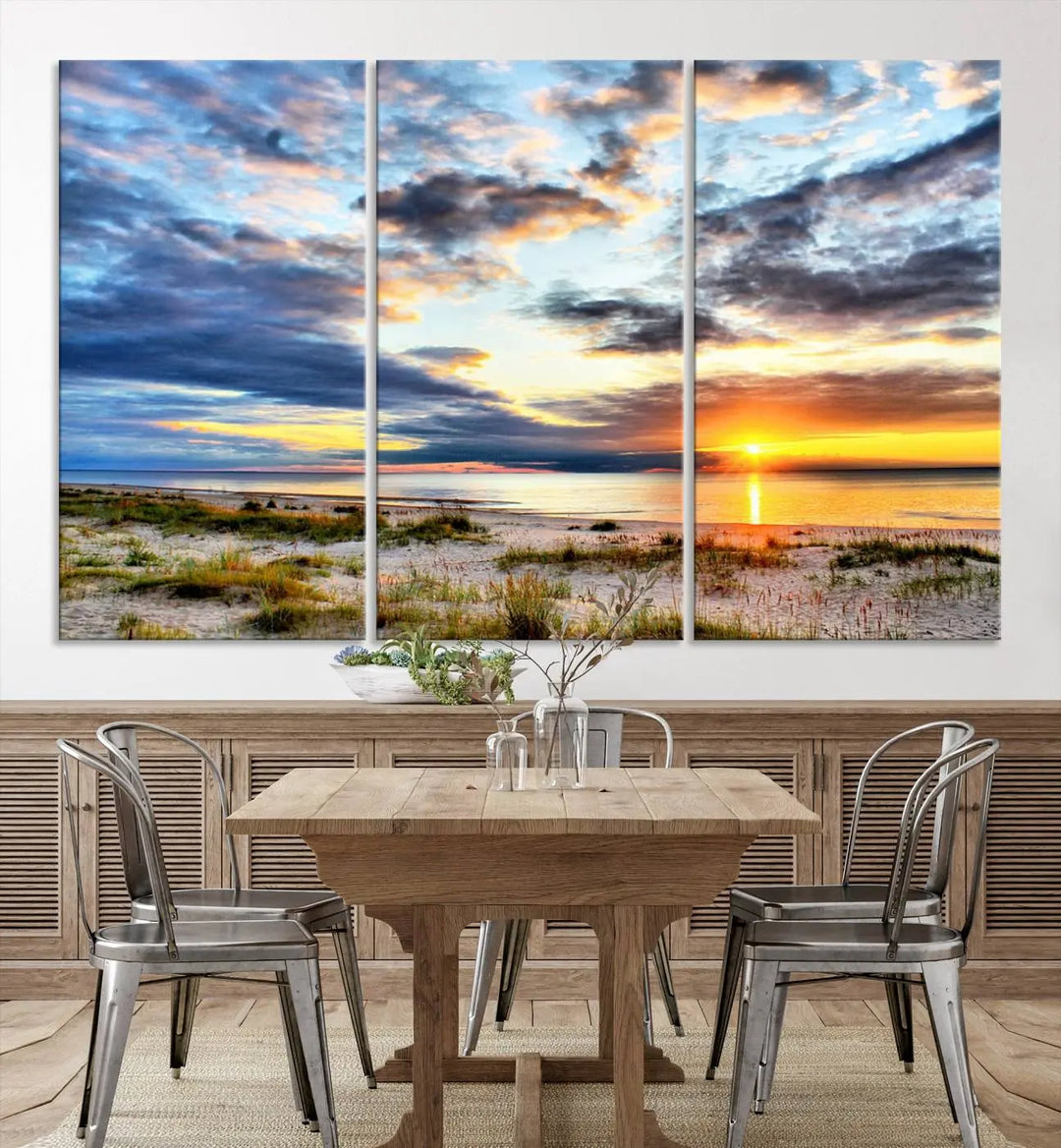 The living room features the Sunset On The Ocean Wall Art Canvas Print, a stunning large triptych depicting a sunset over a beach. This artwork is elegantly displayed on museum-quality canvas with UV-protective coating, ensuring both beauty and durability.