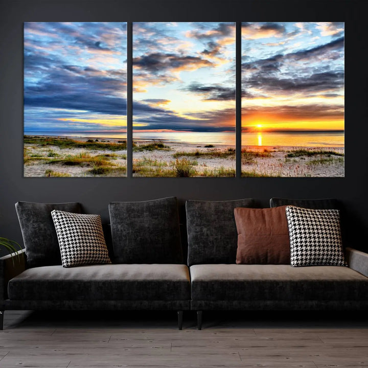 The living room features the Sunset On The Ocean Wall Art Canvas Print, a stunning large triptych depicting a sunset over a beach. This artwork is elegantly displayed on museum-quality canvas with UV-protective coating, ensuring both beauty and durability.