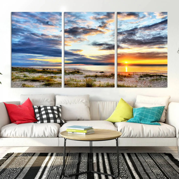 The living room features the Sunset On The Ocean Wall Art Canvas Print, a stunning large triptych depicting a sunset over a beach. This artwork is elegantly displayed on museum-quality canvas with UV-protective coating, ensuring both beauty and durability.