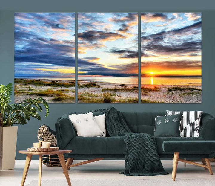 The living room features the Sunset On The Ocean Wall Art Canvas Print, a stunning large triptych depicting a sunset over a beach. This artwork is elegantly displayed on museum-quality canvas with UV-protective coating, ensuring both beauty and durability.