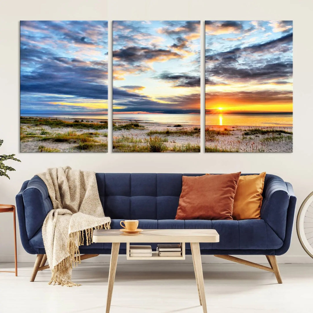 The living room features the Sunset On The Ocean Wall Art Canvas Print, a stunning large triptych depicting a sunset over a beach. This artwork is elegantly displayed on museum-quality canvas with UV-protective coating, ensuring both beauty and durability.