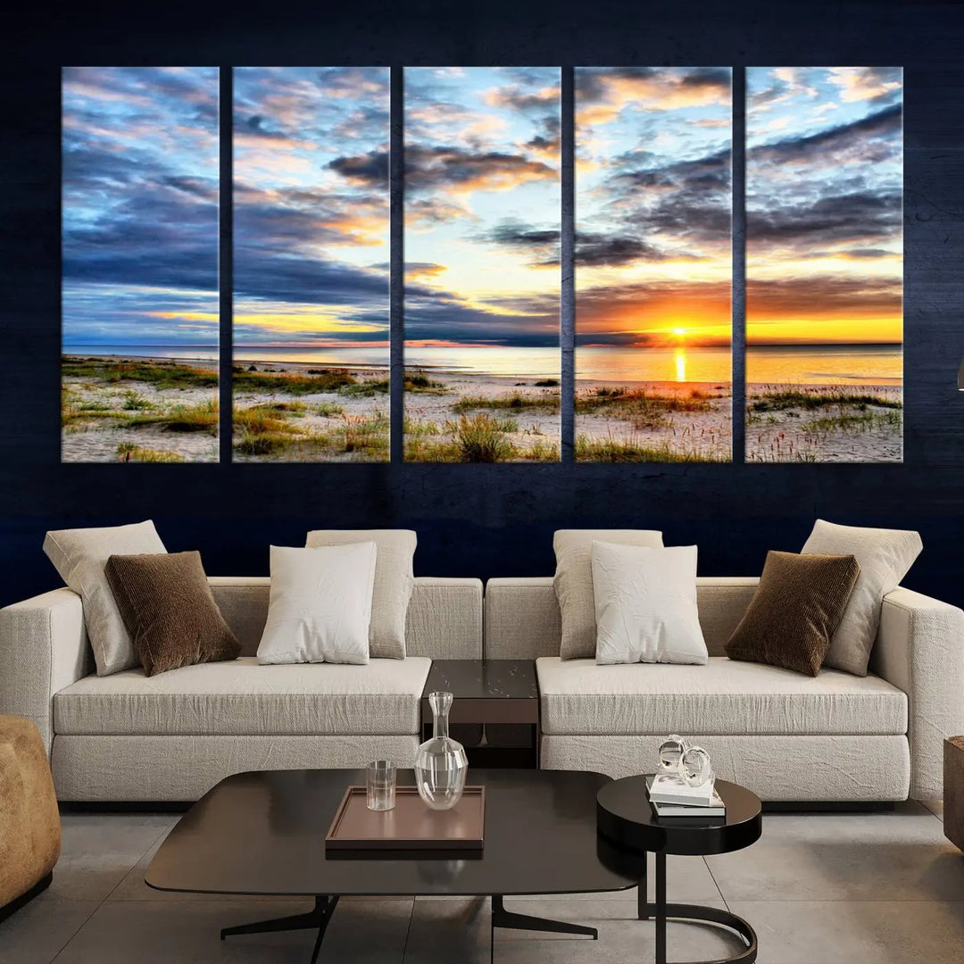 The living room features the Sunset On The Ocean Wall Art Canvas Print, a stunning large triptych depicting a sunset over a beach. This artwork is elegantly displayed on museum-quality canvas with UV-protective coating, ensuring both beauty and durability.