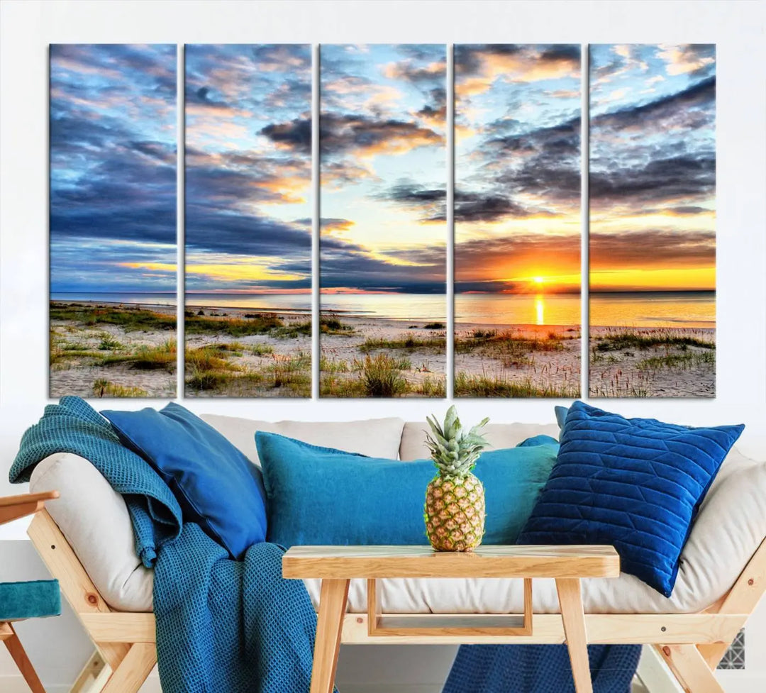 The living room features the Sunset On The Ocean Wall Art Canvas Print, a stunning large triptych depicting a sunset over a beach. This artwork is elegantly displayed on museum-quality canvas with UV-protective coating, ensuring both beauty and durability.