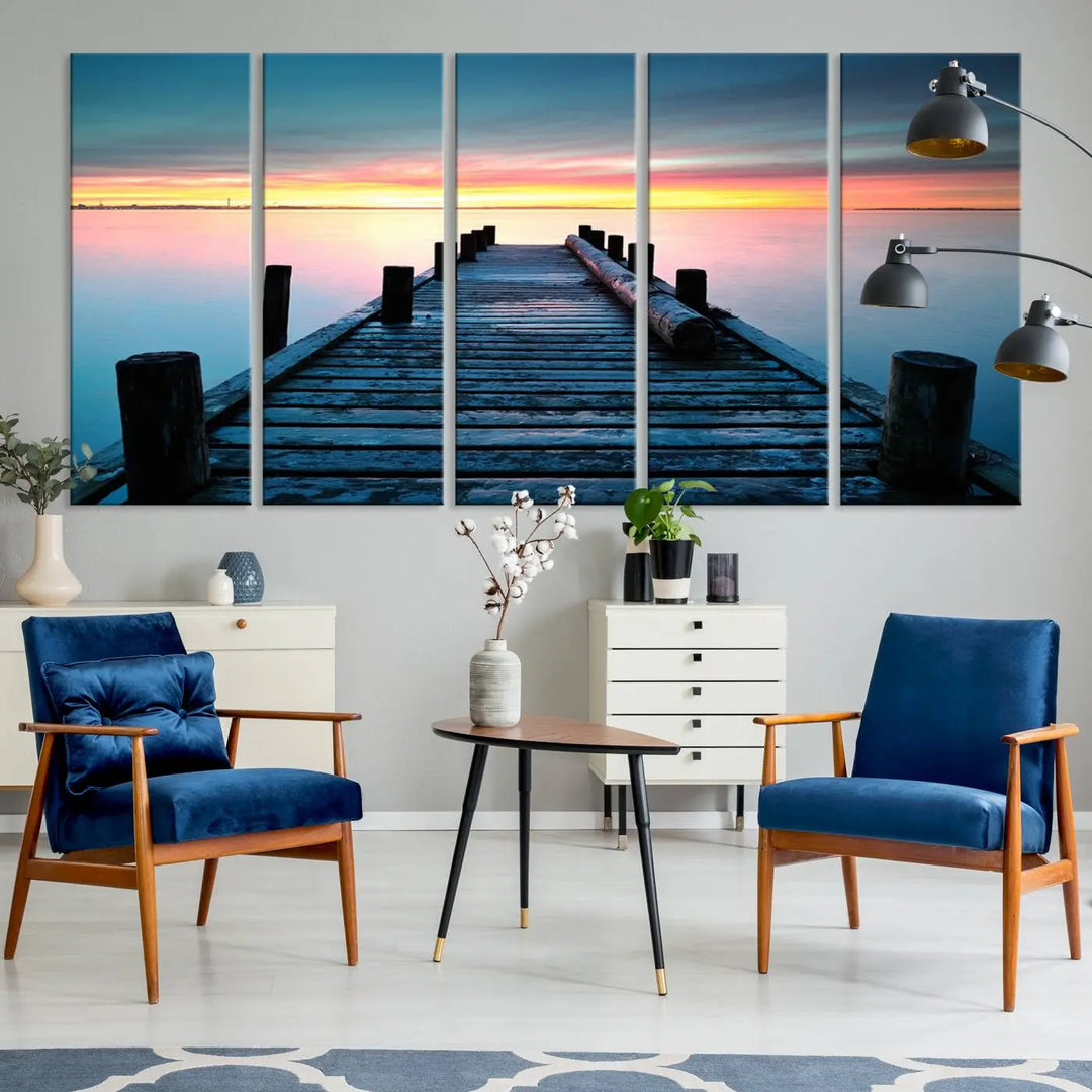 The "Sunset Pier Triptych Canvas Art," a giclee print known for its Canon print quality and gallery wrap finish, captures a wooden pier stretching into a tranquil lake at sunset beneath vibrant orange and blue skies. It makes an ideal centerpiece for coastal-themed art settings.