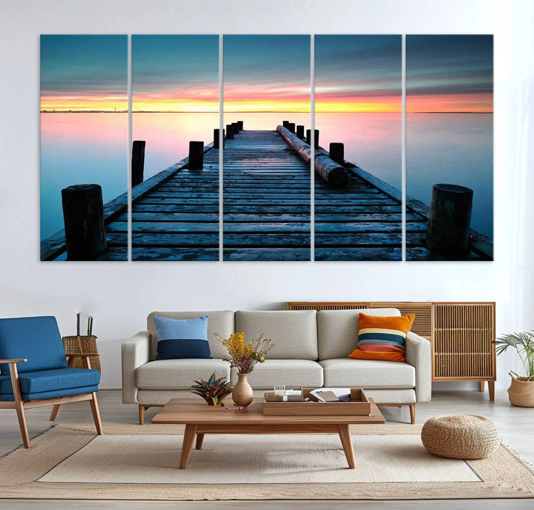 The "Sunset Pier Triptych Canvas Art," a giclee print known for its Canon print quality and gallery wrap finish, captures a wooden pier stretching into a tranquil lake at sunset beneath vibrant orange and blue skies. It makes an ideal centerpiece for coastal-themed art settings.