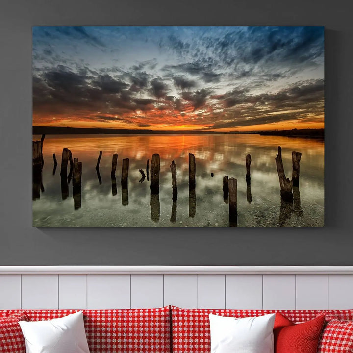 The "Sunset Reflection on Wooden Pier Giclee Canvas Print" is a panoramic wall art piece showcasing serene nature photography with a colorful sunset over water and wooden posts.