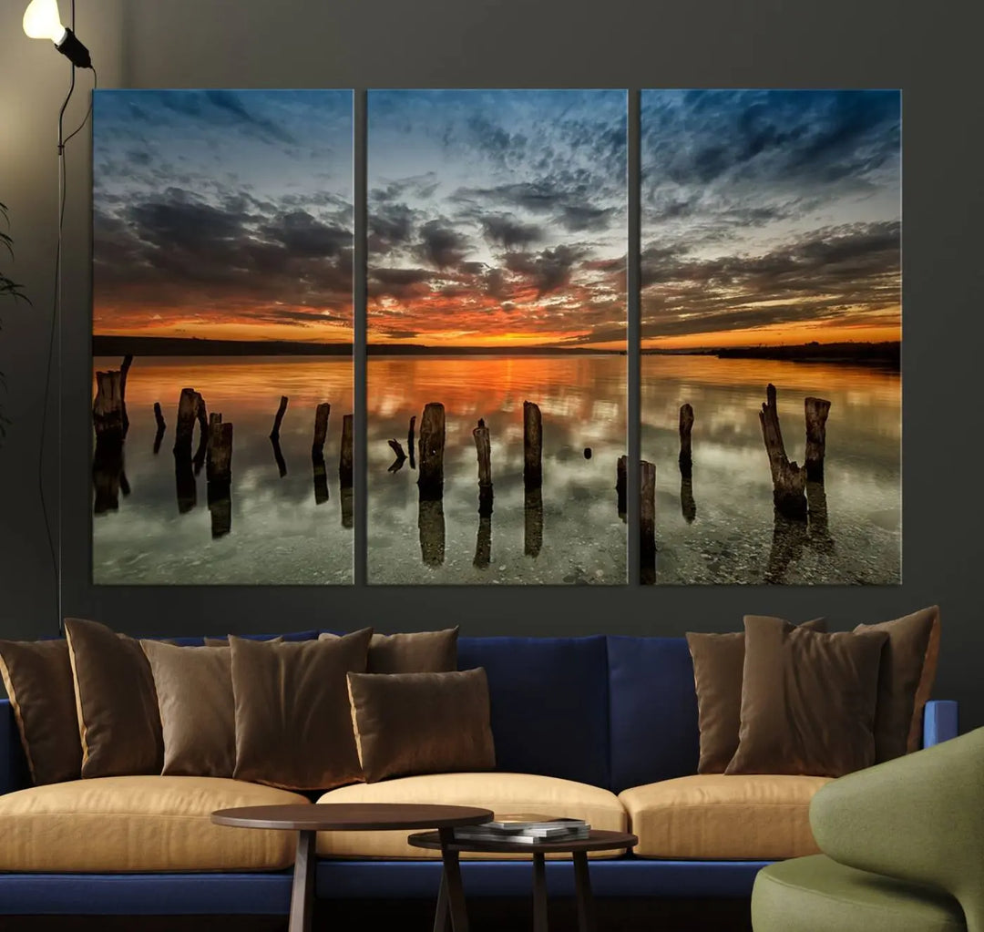 The "Sunset Reflection on Wooden Pier Giclee Canvas Print" is a panoramic wall art piece showcasing serene nature photography with a colorful sunset over water and wooden posts.