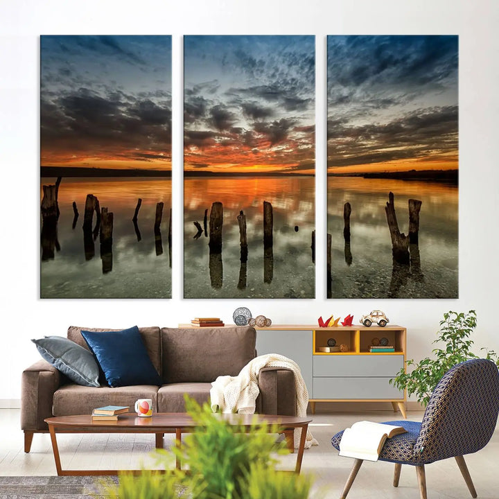 The "Sunset Reflection on Wooden Pier Giclee Canvas Print" is a panoramic wall art piece showcasing serene nature photography with a colorful sunset over water and wooden posts.