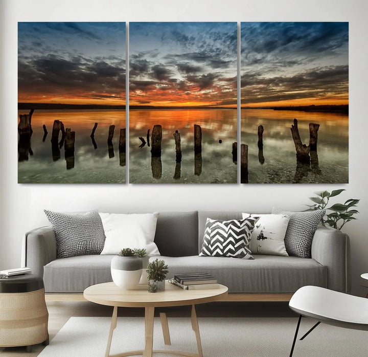 The "Sunset Reflection on Wooden Pier Giclee Canvas Print" is a panoramic wall art piece showcasing serene nature photography with a colorful sunset over water and wooden posts.