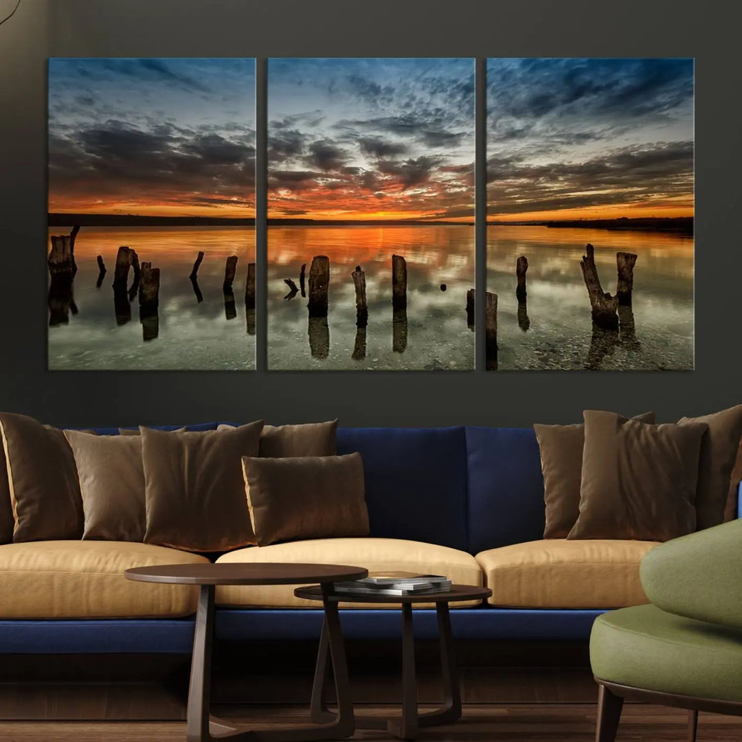 The "Sunset Reflection on Wooden Pier Giclee Canvas Print" is a panoramic wall art piece showcasing serene nature photography with a colorful sunset over water and wooden posts.