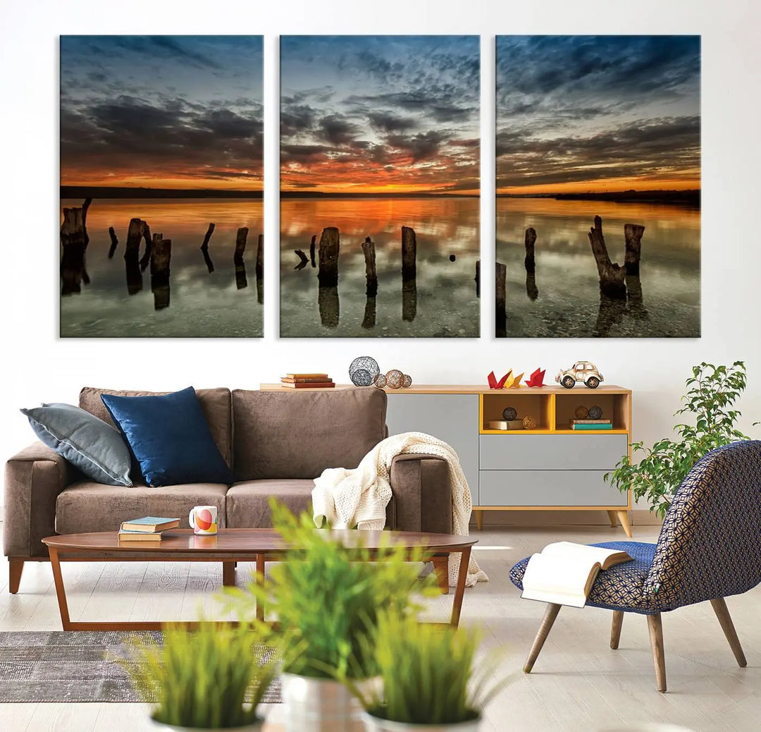 The "Sunset Reflection on Wooden Pier Giclee Canvas Print" is a panoramic wall art piece showcasing serene nature photography with a colorful sunset over water and wooden posts.