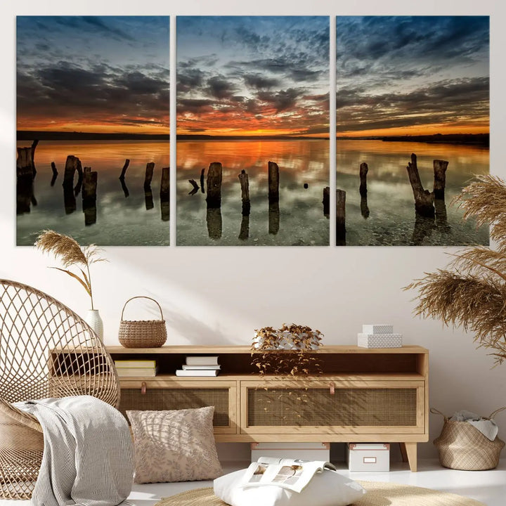 The "Sunset Reflection on Wooden Pier Giclee Canvas Print" is a panoramic wall art piece showcasing serene nature photography with a colorful sunset over water and wooden posts.