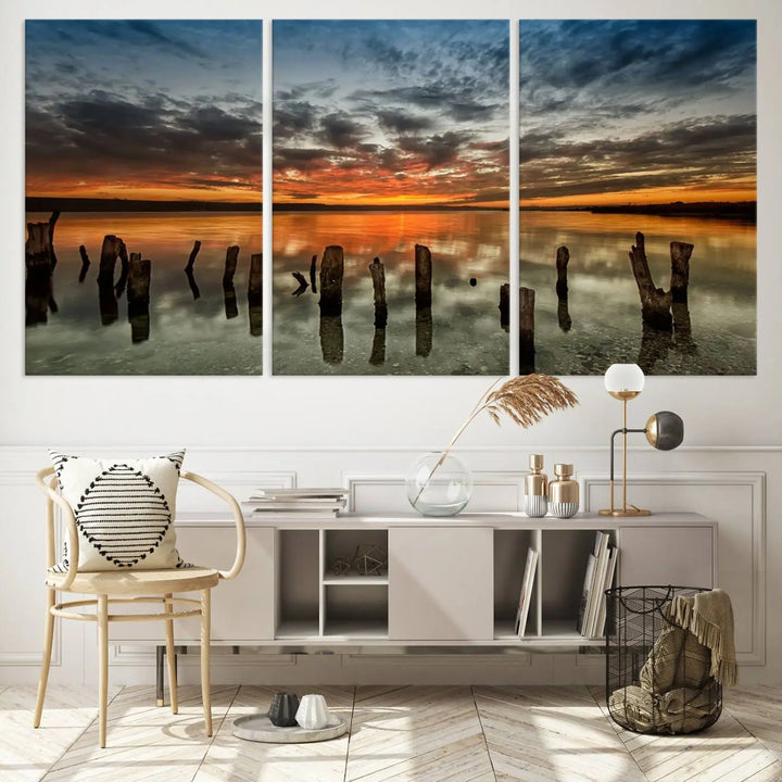 The "Sunset Reflection on Wooden Pier Giclee Canvas Print" is a panoramic wall art piece showcasing serene nature photography with a colorful sunset over water and wooden posts.