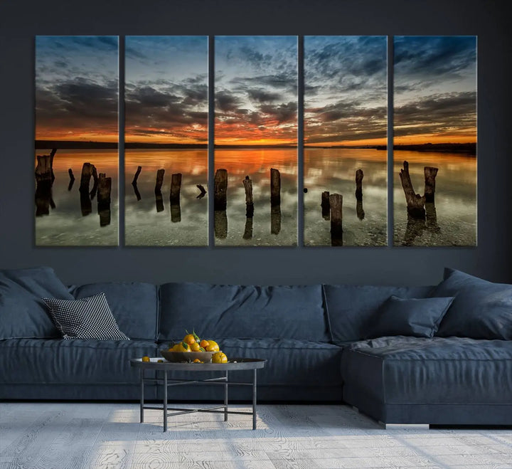 The "Sunset Reflection on Wooden Pier Giclee Canvas Print" is a panoramic wall art piece showcasing serene nature photography with a colorful sunset over water and wooden posts.