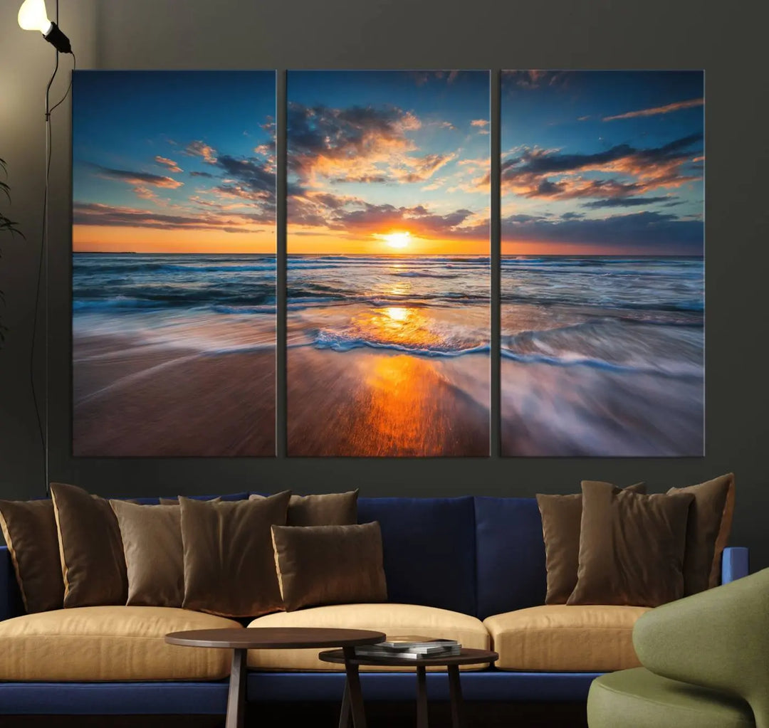 The Sunset on Beach Canvas Wall Art Canvas Print is a triptych depicting a sunset over the ocean. Each piece of this museum-quality polycotton canvas is gallery wrapped and has a UV-protective coating to maintain its vibrant colors. It is displayed on a living room wall.