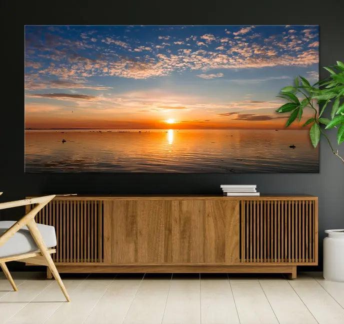 The "Sunset on the Sea Wall Art Canvas Print" graces the space as a stunning triptych, with its museum-quality canvas showcasing a serene sunset over water. The gallery-wrapped edges enhance depth and elegance, creating an ideal centerpiece for any room.