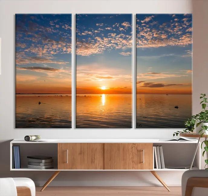 The "Sunset on the Sea Wall Art Canvas Print" graces the space as a stunning triptych, with its museum-quality canvas showcasing a serene sunset over water. The gallery-wrapped edges enhance depth and elegance, creating an ideal centerpiece for any room.