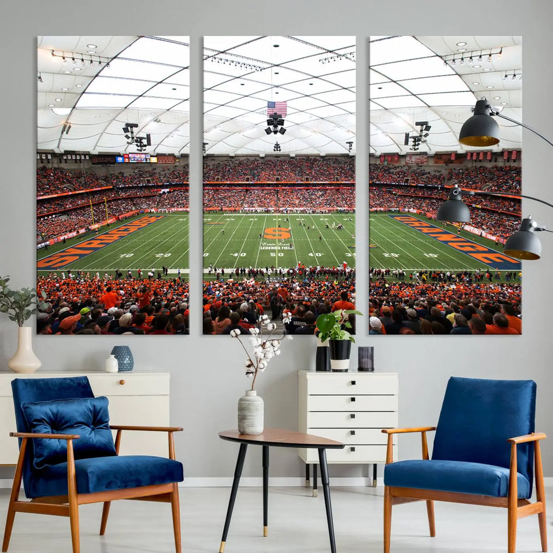 The living room boasts a sizable, three-panel canvas artwork on the wall, depicting the vibrant crowd of the Syracuse University Orange football team at Syracuse JMA Wireless Dome, complete with a gallery-quality finish.