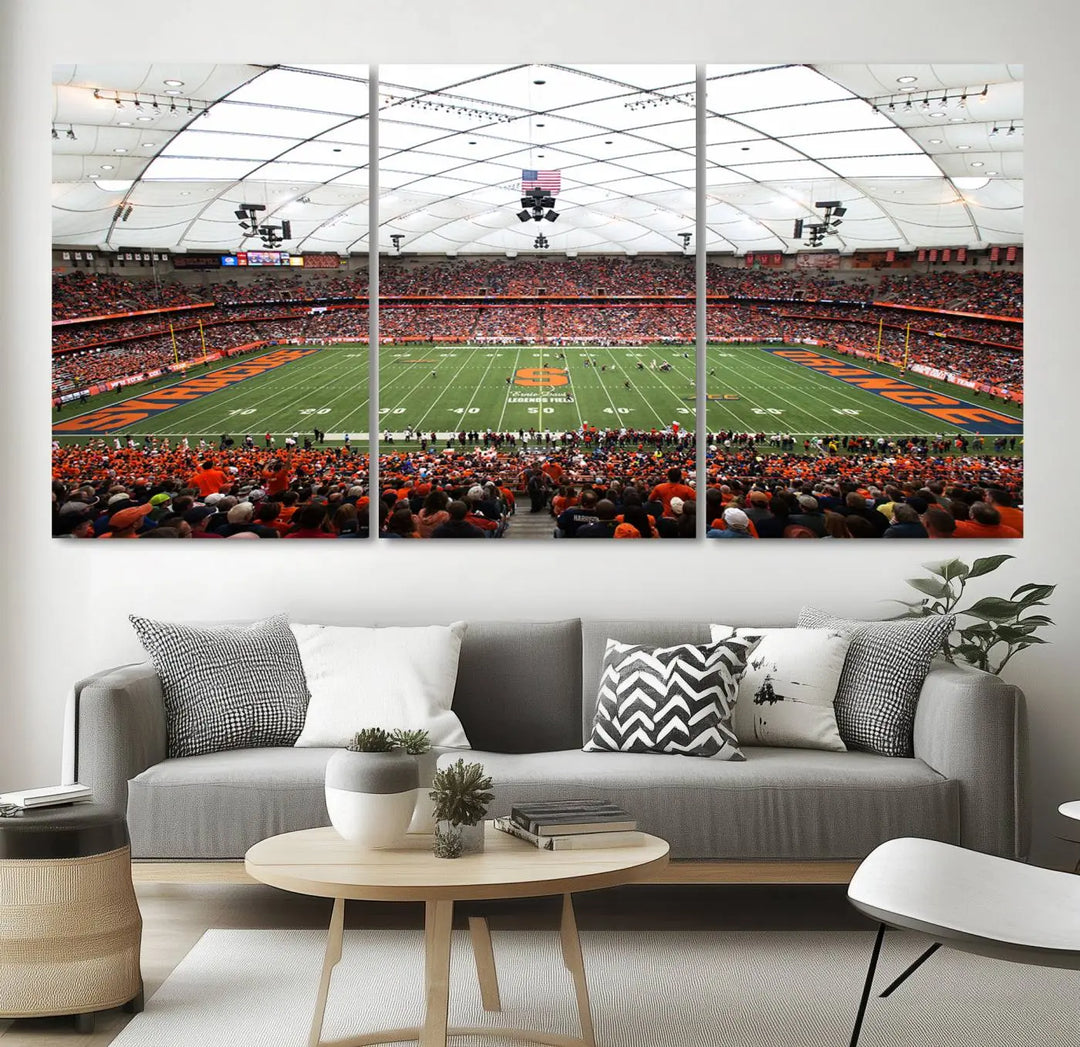 The living room boasts a sizable, three-panel canvas artwork on the wall, depicting the vibrant crowd of the Syracuse University Orange football team at Syracuse JMA Wireless Dome, complete with a gallery-quality finish.