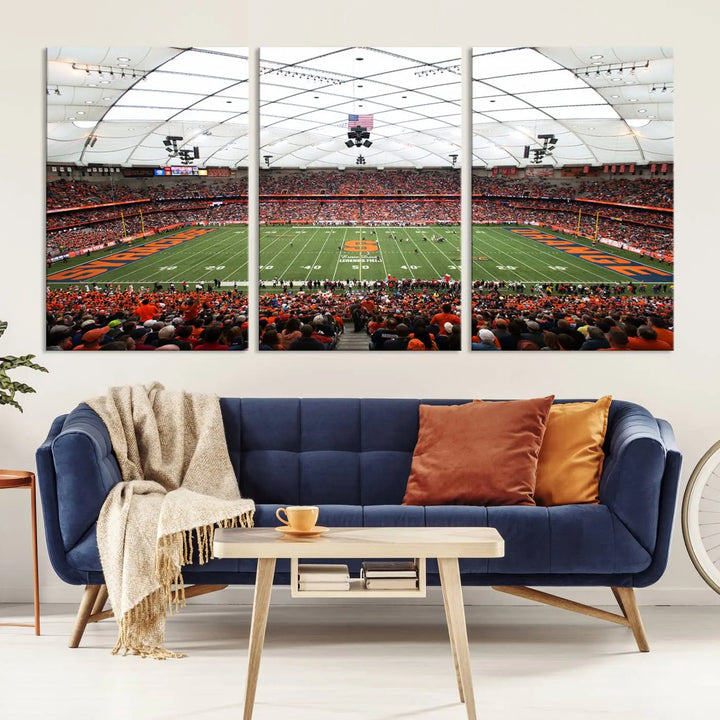 The living room boasts a sizable, three-panel canvas artwork on the wall, depicting the vibrant crowd of the Syracuse University Orange football team at Syracuse JMA Wireless Dome, complete with a gallery-quality finish.