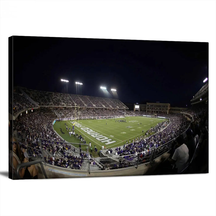 Immerse yourself in the vibrant energy of a packed football stadium at night with bright lights illuminating the field and stands, beautifully captured in the TCU Horned Frogs Football Team Print on premium canvas. This wall art features Fort Worth's Amon G. Carter Stadium.