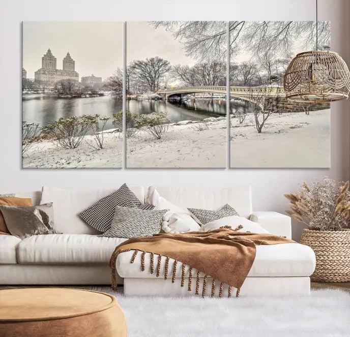 The Bow Bridge in Central Park Canvas Print features a snowy scene with a bridge and city buildings in the background. This museum-quality canvas comes with a UV-protective coating and is ready to hang.