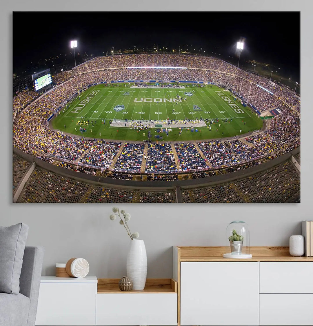 A triptych canvas artwork titled "The University of Connecticut UCONN Huskies Football Team Print" showcases a packed Pratt & Whitney Stadium in East Hartford at night, with a stunning gallery-quality finish.