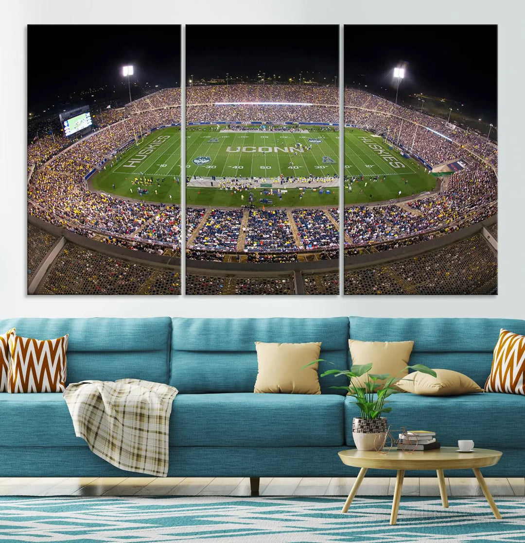 A triptych canvas artwork titled "The University of Connecticut UCONN Huskies Football Team Print" showcases a packed Pratt & Whitney Stadium in East Hartford at night, with a stunning gallery-quality finish.