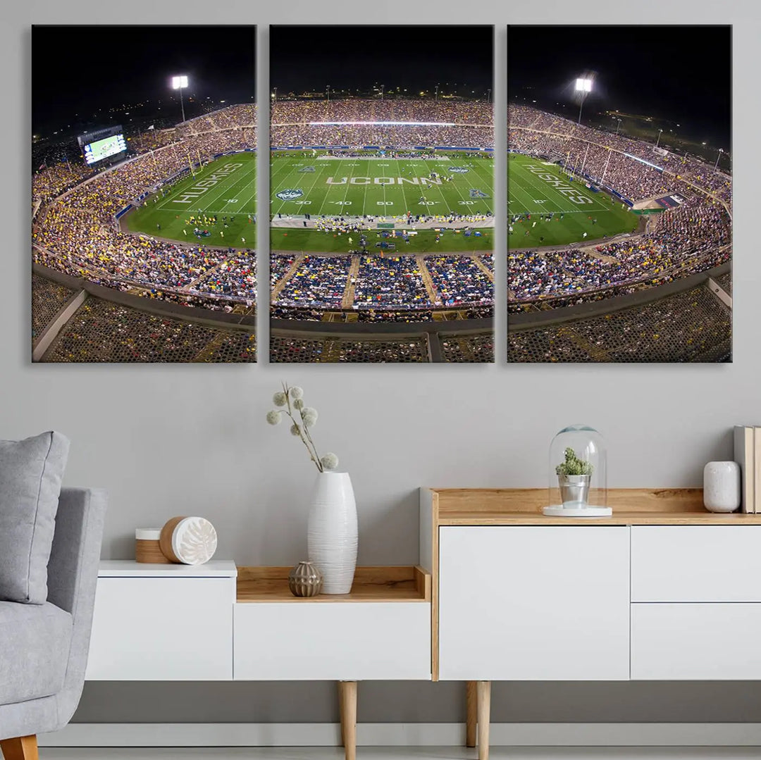 A triptych canvas artwork titled "The University of Connecticut UCONN Huskies Football Team Print" showcases a packed Pratt & Whitney Stadium in East Hartford at night, with a stunning gallery-quality finish.