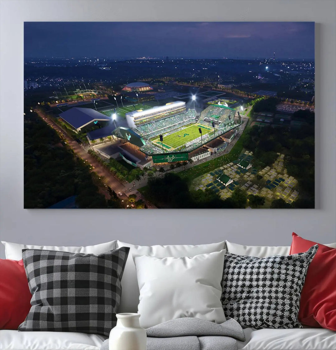 A living room showcasing 'The University of South Florida Bulls Football Team Print' as a triptych wall art highlights the Tampa USF Football Stadium under bright lights at night with a gallery-quality finish.