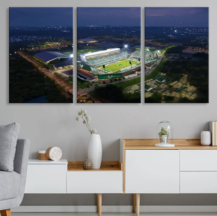 A living room showcasing 'The University of South Florida Bulls Football Team Print' as a triptych wall art highlights the Tampa USF Football Stadium under bright lights at night with a gallery-quality finish.