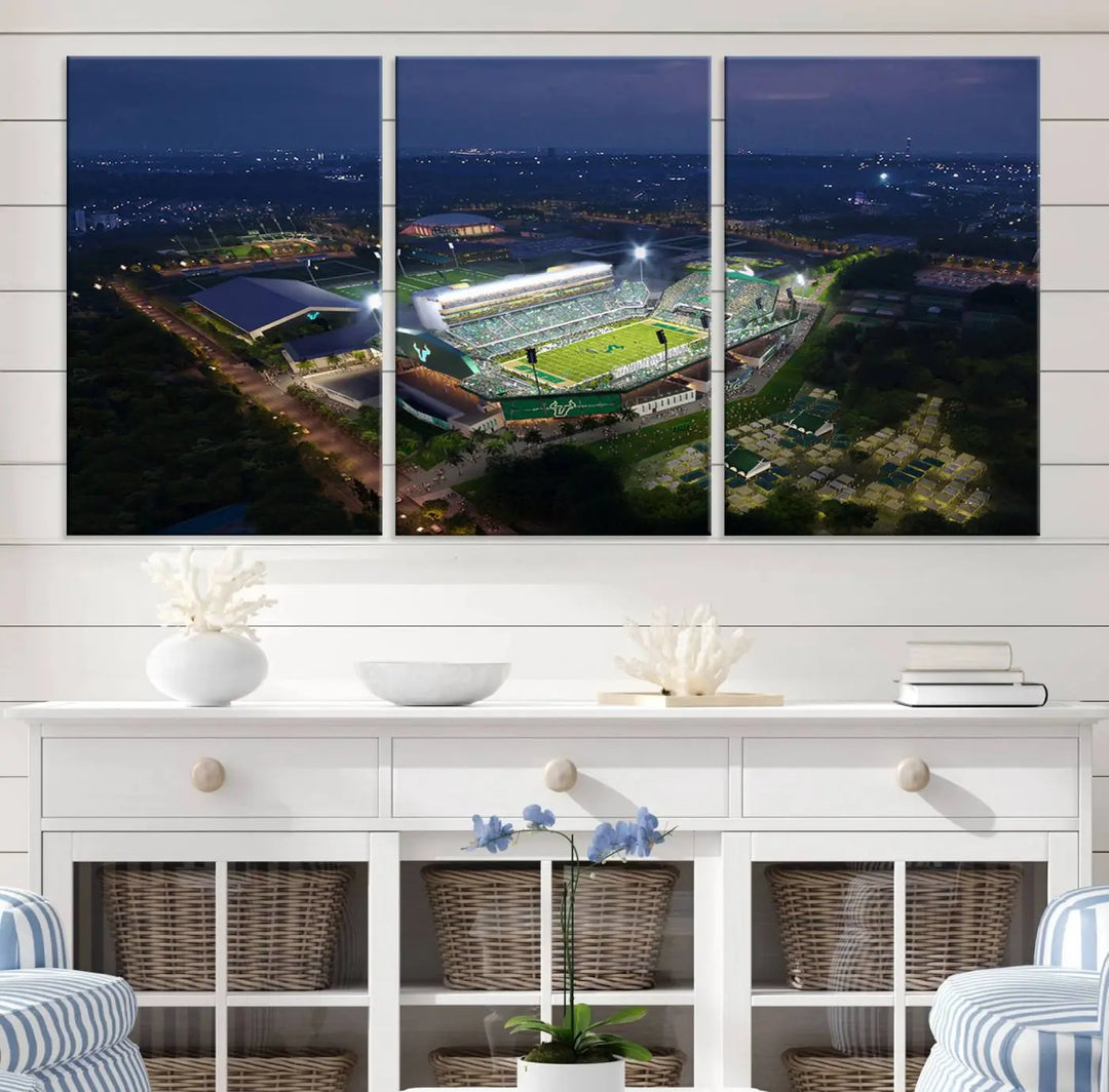 A living room showcasing 'The University of South Florida Bulls Football Team Print' as a triptych wall art highlights the Tampa USF Football Stadium under bright lights at night with a gallery-quality finish.