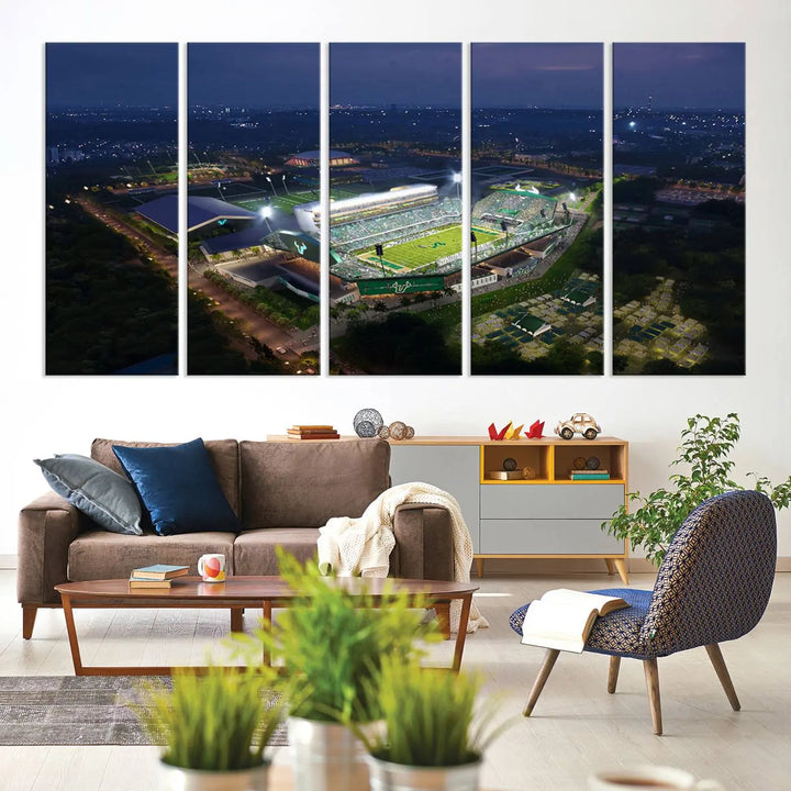 A living room showcasing 'The University of South Florida Bulls Football Team Print' as a triptych wall art highlights the Tampa USF Football Stadium under bright lights at night with a gallery-quality finish.