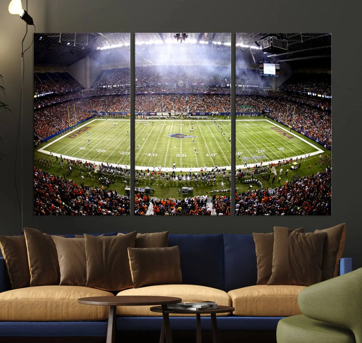 A living room features a striking piece of art on the wall, showcasing high-resolution printing on museum-quality canvas with "The University of Texas at San Antonio Roadrunners Football Team Print - San Antonio Alamodome Wall Art Canvas Print.