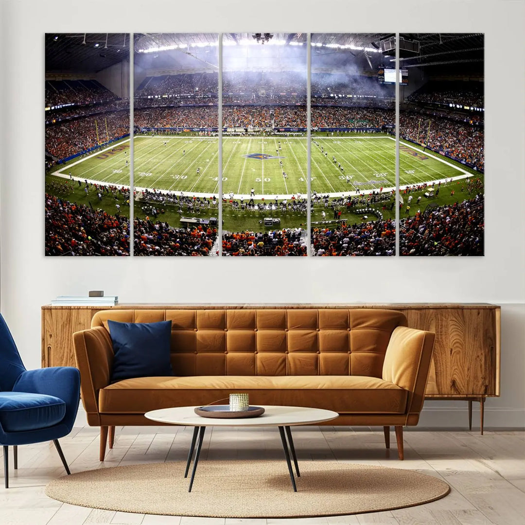 A living room features a striking piece of art on the wall, showcasing high-resolution printing on museum-quality canvas with "The University of Texas at San Antonio Roadrunners Football Team Print - San Antonio Alamodome Wall Art Canvas Print.