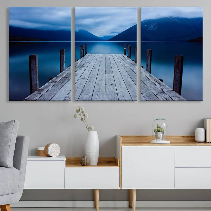 Tranquil lakeside pier triptych canvas art featuring a blue mountain horizon and serene dock. Perfect for modern interiors. High-quality giclee canvas print.