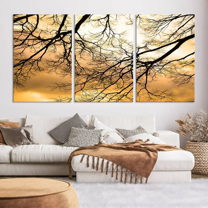 The Tree Branch Wall Art Canvas Print is a triptych depicting tree branches against an orange sky, printed on museum-quality canvases. Each piece comes ready to hang, offering both style and convenience.