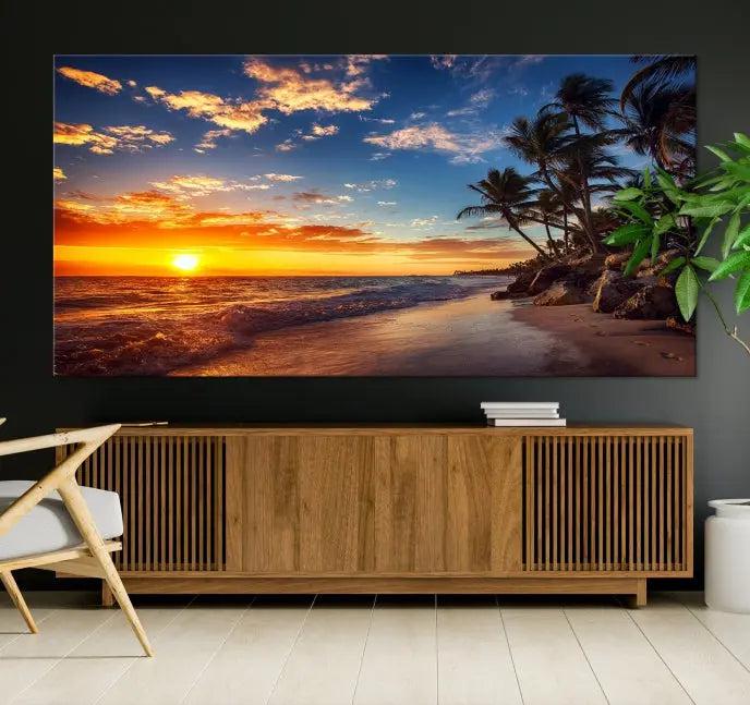 A living room featuring the Tropical Island Wall Art Canvas Print Sunset Artwork Print, a triptych displaying a beach sunset on museum-quality canvas with UV-protective coating, is prepared to hang.