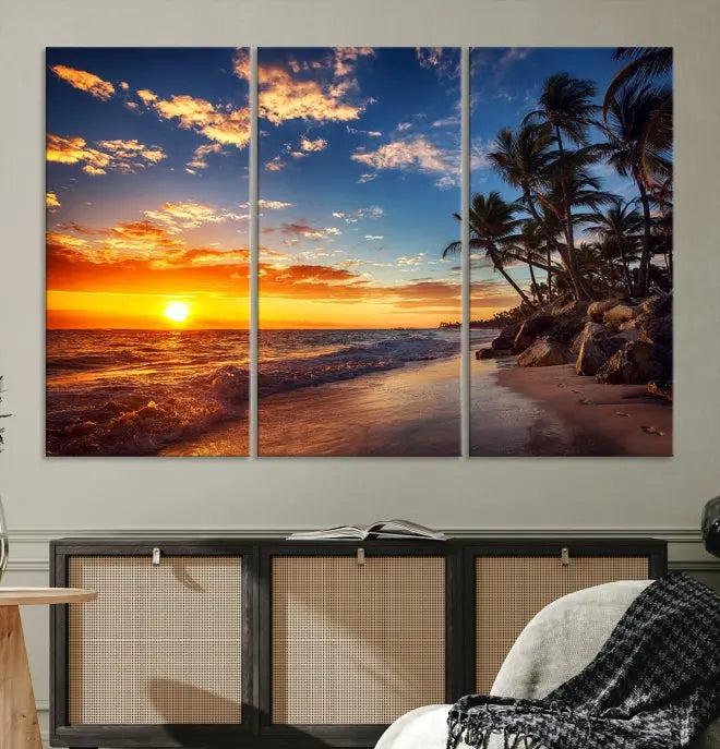 A living room featuring the Tropical Island Wall Art Canvas Print Sunset Artwork Print, a triptych displaying a beach sunset on museum-quality canvas with UV-protective coating, is prepared to hang.