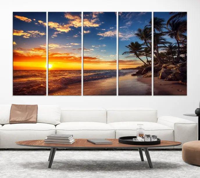 A living room featuring the Tropical Island Wall Art Canvas Print Sunset Artwork Print, a triptych displaying a beach sunset on museum-quality canvas with UV-protective coating, is prepared to hang.