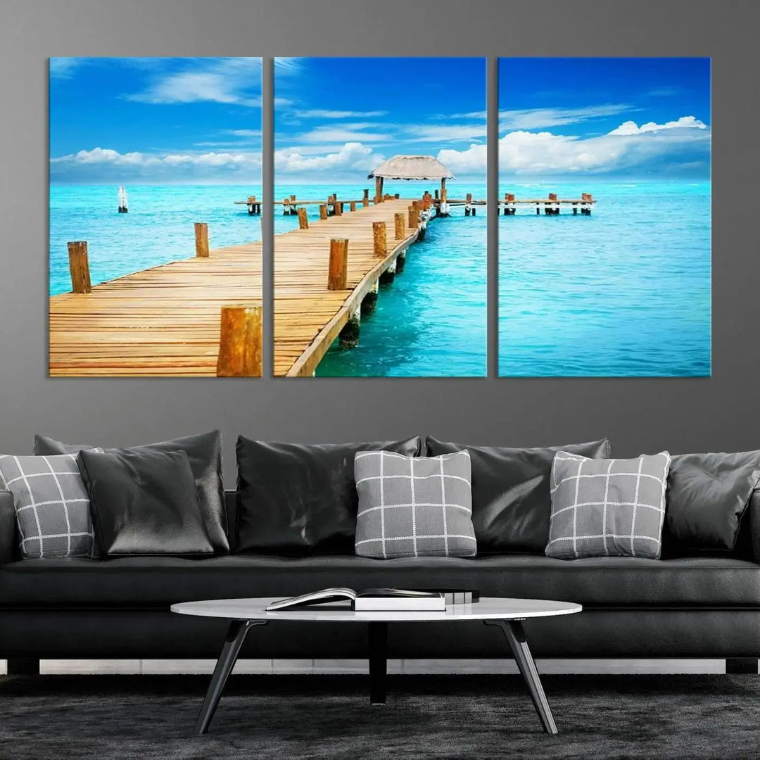 The Tropical Pier Triptych Wall Art is a captivating canvas print featuring a turquoise ocean and a wooden dock, ideal for coastal beach house decor.