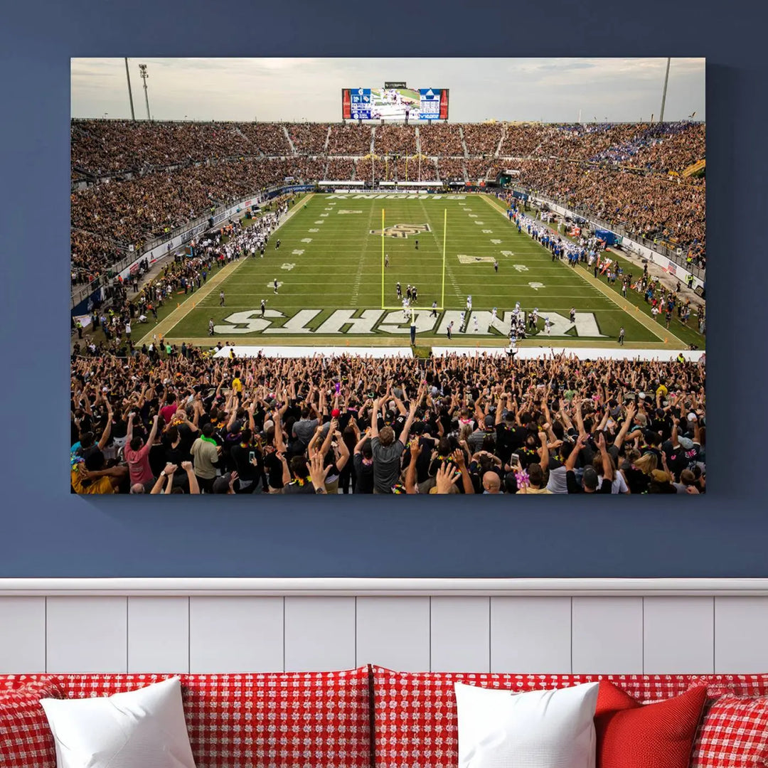 The living room features premium artwork, the "UCF Knights Football Team Print - Orlando FBC Mortgage Stadium Wall Art Canvas Print," a three-panel canvas piece depicting a bustling football stadium. Handmade in the USA, this artwork adds a dynamic and vibrant touch to your space.