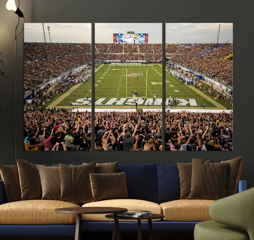 The living room features premium artwork, the "UCF Knights Football Team Print - Orlando FBC Mortgage Stadium Wall Art Canvas Print," a three-panel canvas piece depicting a bustling football stadium. Handmade in the USA, this artwork adds a dynamic and vibrant touch to your space.