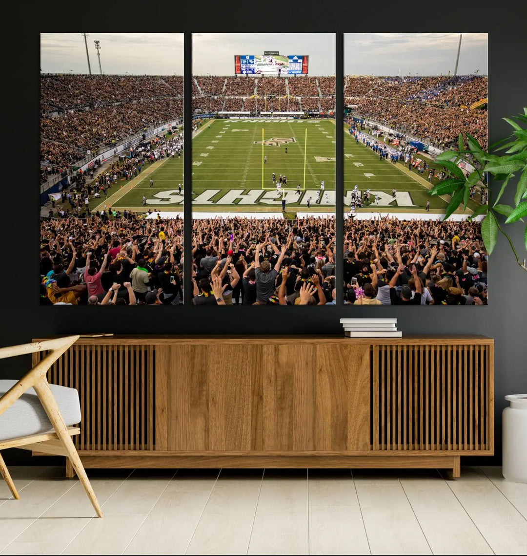 The living room features premium artwork, the "UCF Knights Football Team Print - Orlando FBC Mortgage Stadium Wall Art Canvas Print," a three-panel canvas piece depicting a bustling football stadium. Handmade in the USA, this artwork adds a dynamic and vibrant touch to your space.